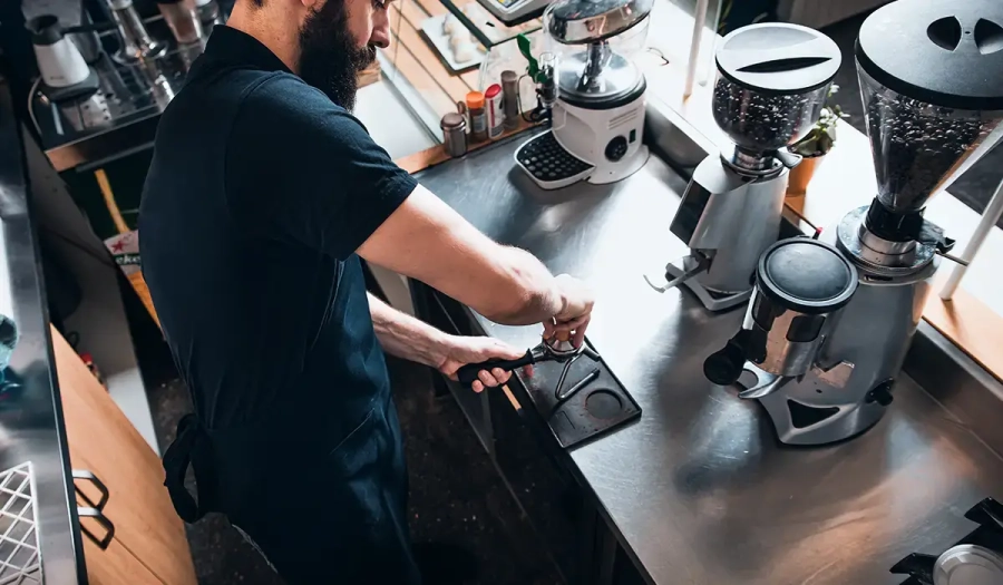 Barista alle prese con il rito della preparazione del caffè espresso dietro al bancone del bar