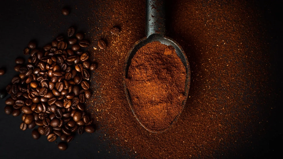 Cucchiaio con caffè macinato e chicchi di caffè