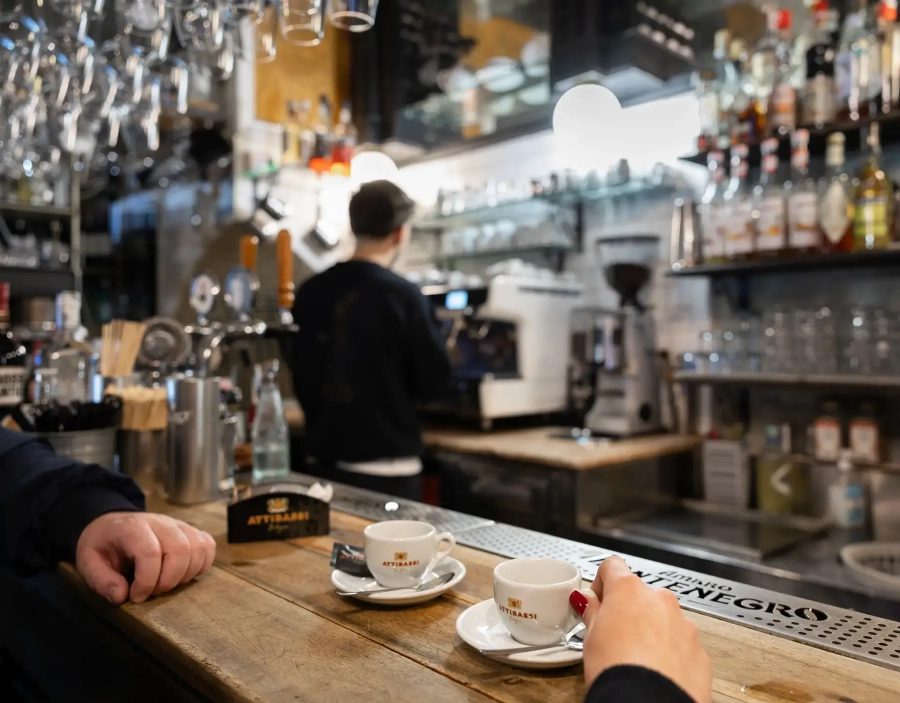 Due persone prendono il caffè Attibassi al bancone del bar