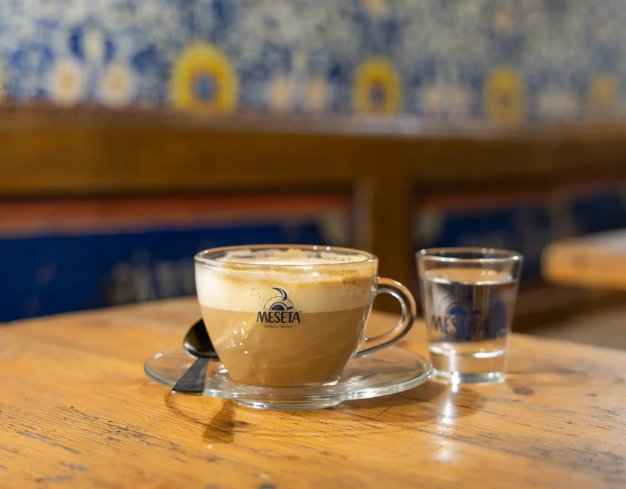 Tazza di cappuccino Meseta, con bicchier d'acqua sopra ad un tavolo del bar